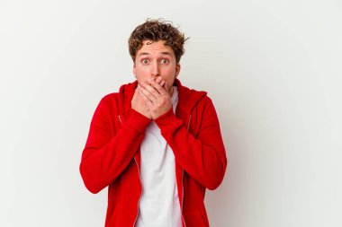 Beyaz arka planda izole edilmiş genç beyaz adam elleriyle ağzını kapatırken şok oldu..
