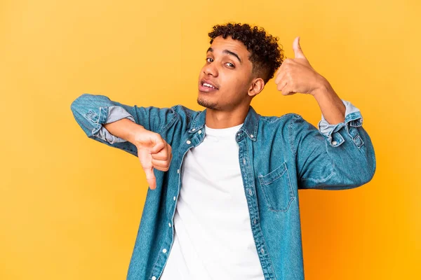 Genç Afro-Amerikalı kıvırcık adam, mor üzerine izole edilmiş baş parmağını kaldırıyor ve baş parmağını aşağı gösteriyor, zor seçim konsepti.