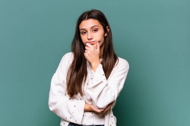 Mavi arka planda izole edilmiş genç Hintli kadın şüpheli, belirsiz, seni muayene ediyor..