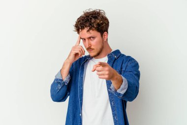 Beyaz arka planda izole edilmiş genç beyaz bir adam şakağı parmağıyla işaret ediyor, düşünüyor ve bir göreve odaklanıyor..