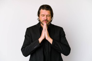 Beyaz arka planda izole edilmiş orta yaşlı bir Hollandalı el ele tutuşmuş, ağzı yakınken dua ediyor, kendinden emin hissediyor..