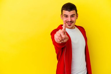Sarı arka planda izole genç beyaz adam parmak ile bir numara gösteren.