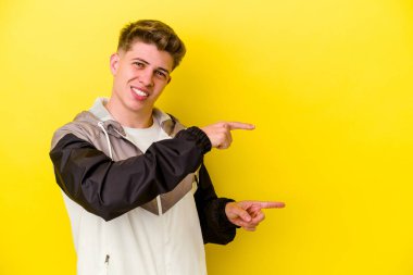 Sarı arka planda izole edilmiş genç beyaz adam işaret fişekleriyle işaret ederek heyecanlanıyor..
