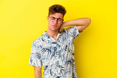 Sarı arka planda izole edilmiş genç beyaz bir adam stresten dolayı boynu ağrıyor, masaj yapıyor ve elle dokunuyor..