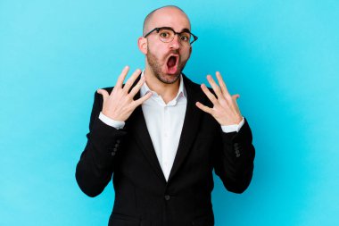 Genç beyaz tenli kel adam mavi arka planda izole edilmiş. 10 numarayı elleriyle gösteriyor..