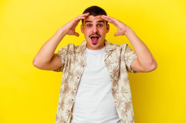 Sarı arka planda izole edilmiş genç beyaz adam zaferi veya başarıyı kutluyor, şaşırıyor ve şok oluyor..