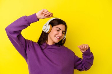 Pembe arka planda müzik dinleyen beyaz bir kadın özel bir günü kutluyor, atlıyor ve enerjiyle kollarını kaldırıyor..