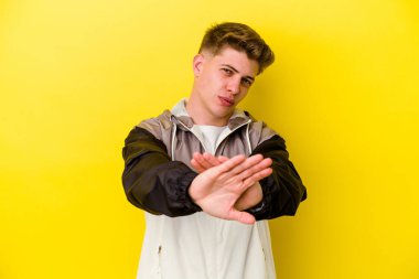 Sarı arka planda izole edilmiş genç beyaz adam elini uzatmış, dur işareti göstererek seni engelliyor..