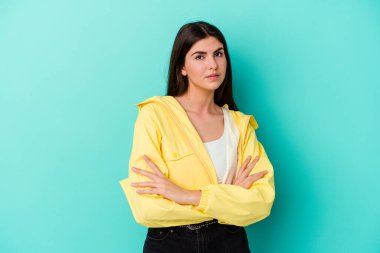 Kafkasyalı genç bir kadın mavi arka planda izole edilmiş şüpheli, belirsiz, seni muayene ediyor..