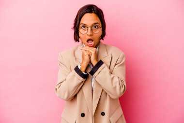 Pembe arka planda izole edilmiş genç iş kadını şans diliyor, şaşırıyor ve ağzını açıyor..