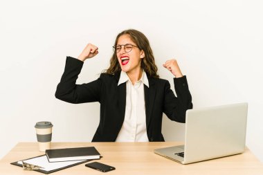 Genç Kafkas iş kadını masasında çalışıyor. Zaferden sonra yumruğunu kaldırıyor. Kazanan konsept..