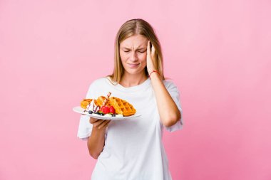 Genç Rus kadın waffle yiyor, tapınaklara dokunuyor ve baş ağrısı çekiyor..
