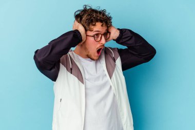 Mavi arka planda izole edilmiş gözlük takan genç beyaz adam çığlık atıyor, çok heyecanlı, tutkulu, bir şeyden memnun..