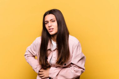 Sarı arka planda izole edilmiş genç bir Hintli kadın. Karaciğer ağrısı, mide ağrısı var..