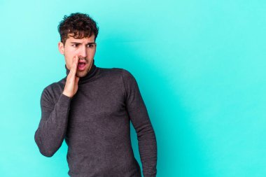 Mavi arka planda izole edilmiş genç beyaz bir adam gizli bir sıcak fren haberi veriyor ve yana bakıyor.