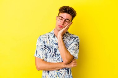 Sarı arka planda izole edilmiş genç beyaz adam sıkılmış, yorgun ve dinlenmeye ihtiyacı var..