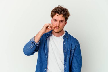 Beyaz arka planda izole edilmiş beyaz tenli genç bir adam parmakları dudaklarında bir sır saklıyor..