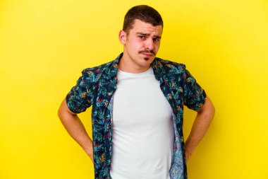 Sarı arka planda izole edilmiş, kafası karışmış, şüpheli ve güvensiz genç beyaz bir adam..