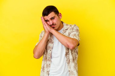 Sarı arka planda izole edilmiş genç beyaz adam esniyor. Ağzı eliyle kapatan yorgun bir hareket sergiliyor..