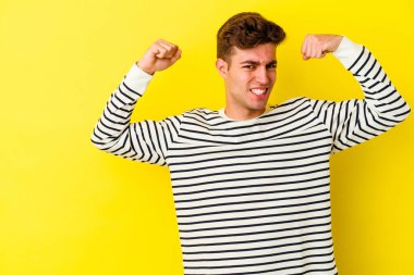 Sarı arka planda izole edilmiş genç beyaz adam zaferden sonra yumruğunu kaldırıyor, kazanan konsept..