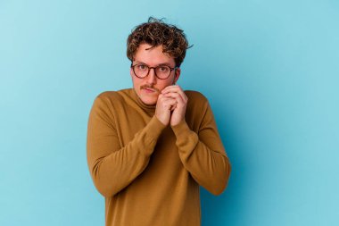 Gözlüklü genç beyaz adam mavi arka planda izole edilmiş korkmuş ve korkmuş..