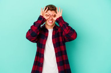 Kafkasyalı genç adam mavi arka planda izole edildi. Heyecanlı görünüyor..