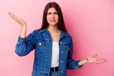 Pembe arka planda soyutlanmış beyaz bir kadın. Kafası karışmış ve omuz silkiyor. Kopya alanını tutmak için..