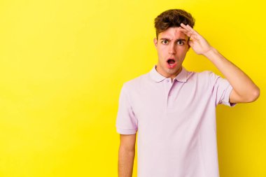 Sarı arka planda izole edilmiş genç beyaz adam yüksek sesle bağırıyor, gözleri açık ve elleri gergin tutuyor..