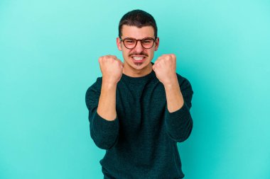 Mavi arka planda izole edilmiş genç beyaz adam gergin elleriyle çığlık atıyor..