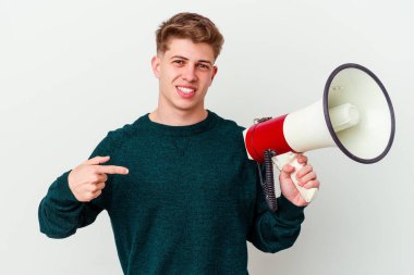 Beyaz arka planda izole edilmiş megafon tutan genç beyaz bir adam gömlek fotokopi alanını işaret ediyor, gururlu ve kendinden emin.