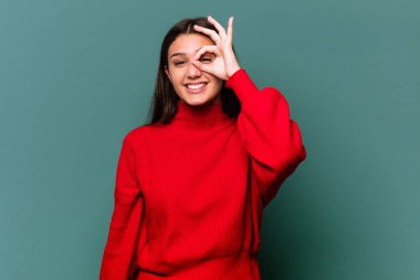 Genç Hintli bir kadın mavi arka planda izole edilmiş. Heyecanlı..