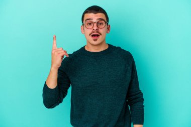 Kafkasyalı genç bir adam mavi arka planda izole edilmiş. Bir fikri, ilham verici bir fikri var..