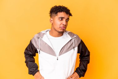 Genç Afro-Amerikalı kıvırcık adam, mor üzerine izole edilmiş, kafası karışmış, şüpheli ve güvensiz hissediyor..