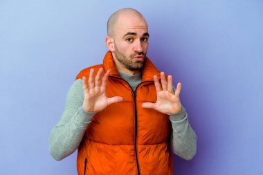 Mor arka planda izole edilmiş beyaz kel bir adam iğrenme hareketi gösteren birini reddediyor..