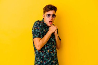 Hawaii gömleği giyen genç beyaz adam sarı arka planda izole edilmiş korkmuş ve korkmuş..
