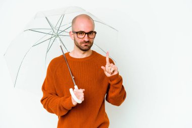 Elinde şemsiye tutan genç kel bir adam bir numarayı parmağıyla gösteriyor..