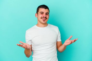 Mavi arka planda izole edilmiş beyaz bir genç hoş bir yüz ifadesi sergiliyor..