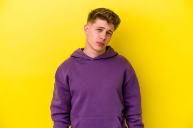 Kafkasyalı genç adam sarı arka planda izole edilmiş üzgün, ciddi yüzlü, mutsuz ve hoşnutsuz..