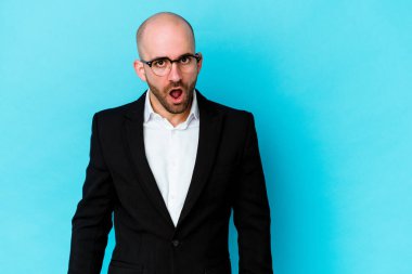Genç, beyaz, kel bir adam mavi arka planda izole edildi. Gördüğü bir şey yüzünden şok oldu..