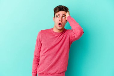 Mavi arka planda izole genç beyaz adam şok oldu, o önemli bir toplantı hatırladı.