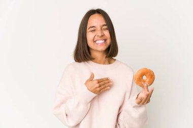 Genç İspanyol kadın donut yerken yüksek sesle gülüyor elini göğsüne koyuyor..