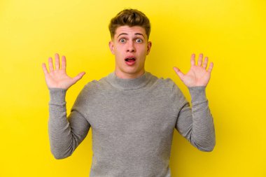 Sarı arka planda izole edilmiş genç beyaz adam gökyüzüne haykırıyor, yukarı bakıyor, hayal kırıklığına uğramış..