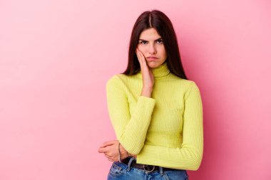 Pembe arka planda izole edilmiş genç beyaz kadın üzgün ve düşünceli, fotokopi alanına bakıyor..