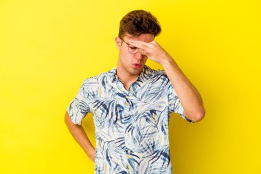Kafkasyalı genç adam sarı arka planda izole edilmiş, başı ağrıyor, yüzüne dokunuyor..