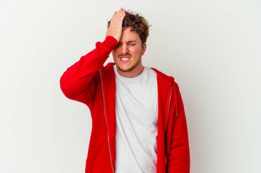 Beyaz arka planda izole edilmiş genç beyaz bir adam bir şeyi unutuyor. Alnına avuç içi ve gözlerini kapayarak vuruyor..