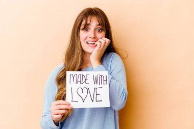 Elinde aşk tabelasından yapılmış, tırnak yiyen, gergin ve endişeli genç bir beyaz kadın var..