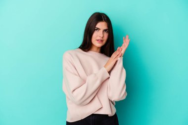 Mavi arka planda izole edilmiş genç beyaz kadın enerjik ve rahat hissediyor, ellerini ovuşturuyor..