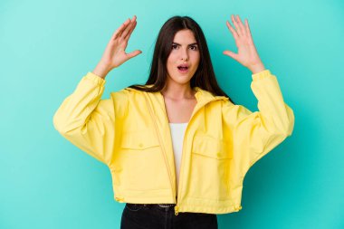 Mavi arka planda izole genç beyaz kadın zaferi ya da başarıyı kutluyor, şaşırıyor ve şok oluyor..