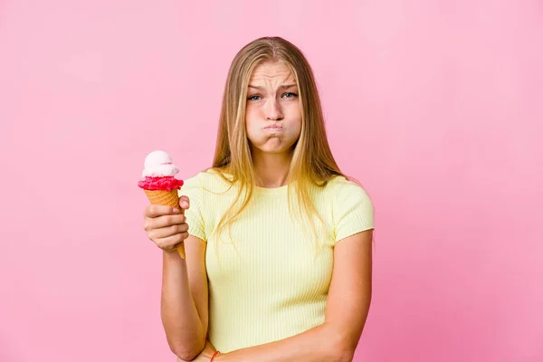 Young russian woman eating an ice cream isolated blows cheeks, has tired expression. Facial expression concept.