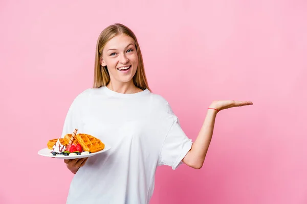 一个年轻的俄罗斯女人吃着一个被隔离的华夫饼 手掌上有一个复制的空间 腰部有另一只手 — 图库照片